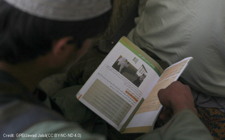 An Afghan boy reading a text book