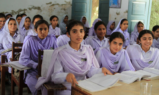 A class of girls in lilac coloured uniform sitting at desks with text books open