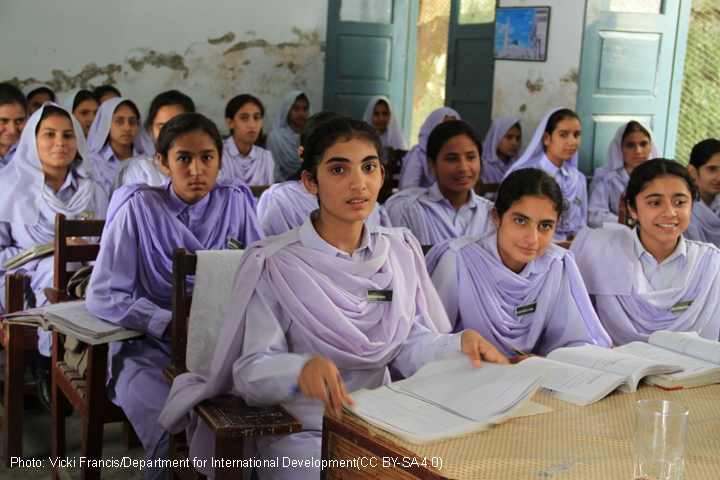 A class of girls in lilac coloured uniform sitting at desks with text books open