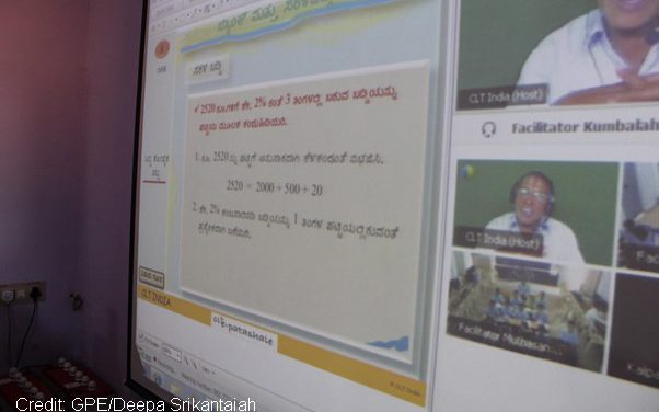 Photo of a computer screen with shared lesson and teacher and pupil with headsets and mics