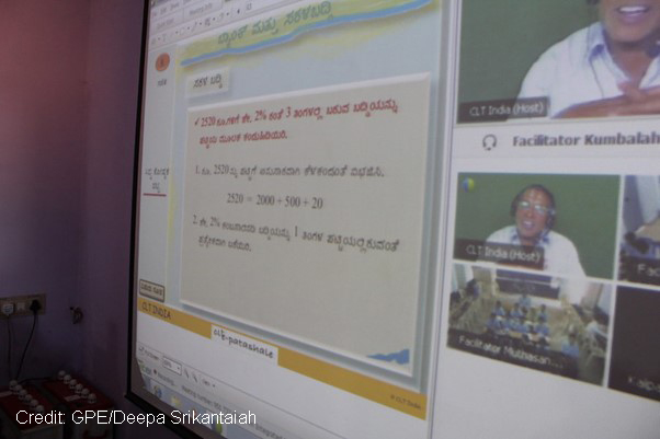 Photo of a computer screen with shared lesson and teacher and pupil with headsets and mics