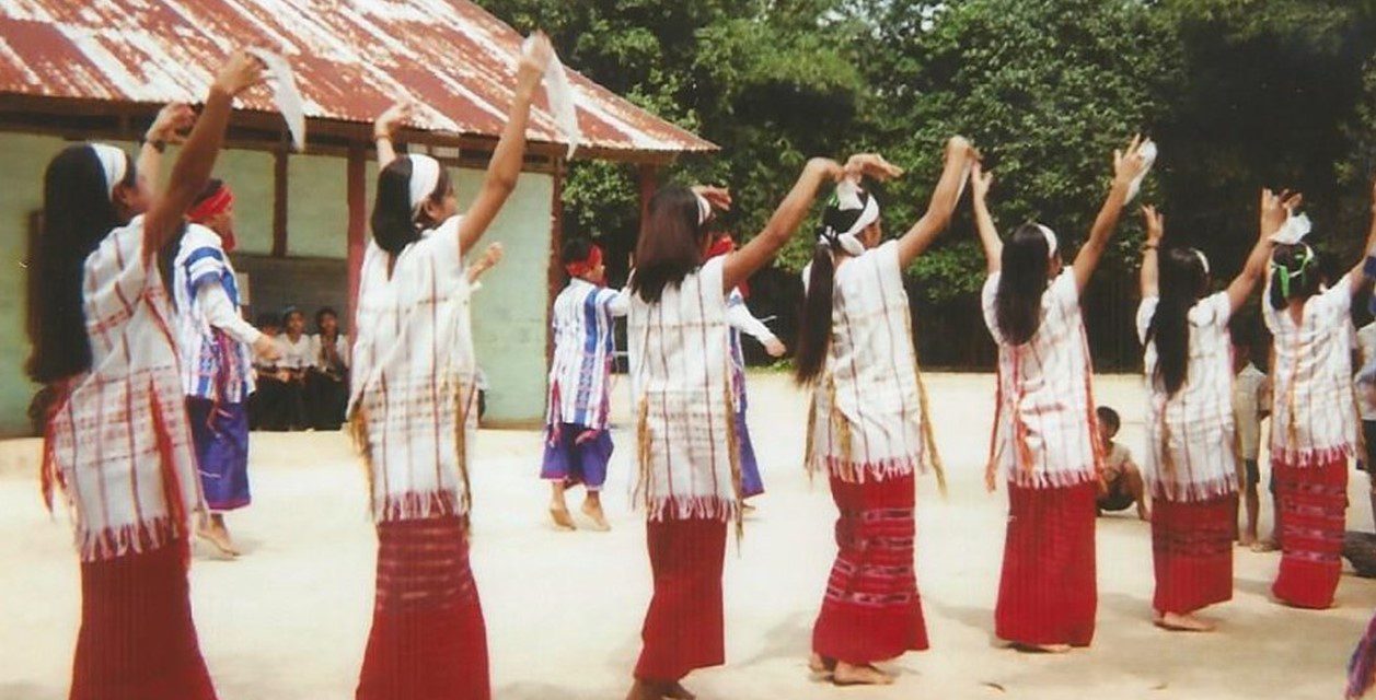 Women dancing in a village location wearing traditional dress