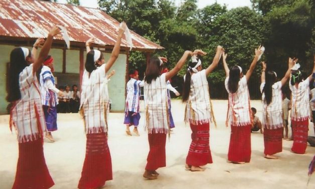 Women dancing in a village location wearing traditional dress
