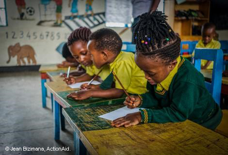 Primary School children wearing green and mustard uniform in a classroom in Rwanda