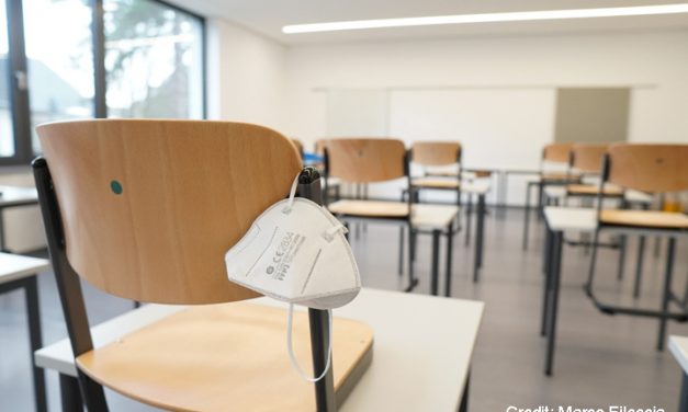 Face mask hanging off the back of a chair in an empty classroom