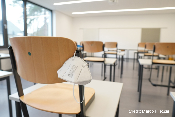 Face mask hanging off the back of a chair in an empty classroom