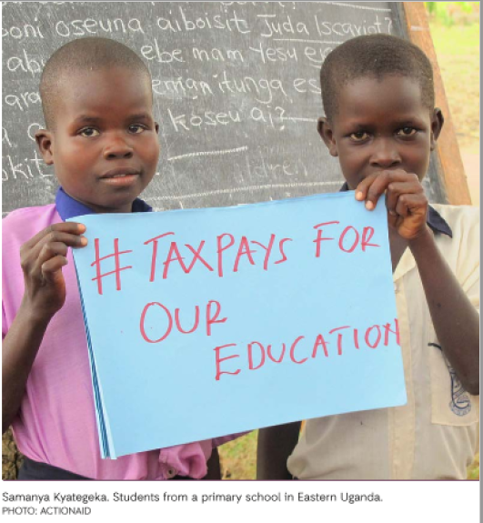Ugandan boys holding up a sign saying #TAX PAYS FOR OUR EDUCATION