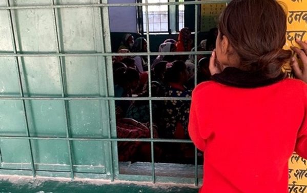 A girl curiously listening to interactions between mothers and teacher, from outside the room, at a school in Sitapur, India.