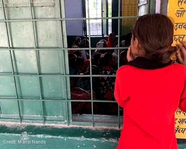 A girl curiously listening to interactions between mothers and teacher, from outside the room, at a school in Sitapur, India.