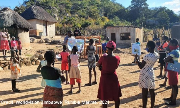 Teaching volunteer holds an informal community learning circle class outside in a rural village with social distancing and masks, Zimbabwe.