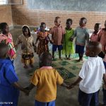 Children singing and dancing in a ring n their pre-school classroom at Jean de la Mennais School in Burera district, rural Rwanda.
