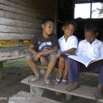 Two boys and a girl reading on a step, Honduras