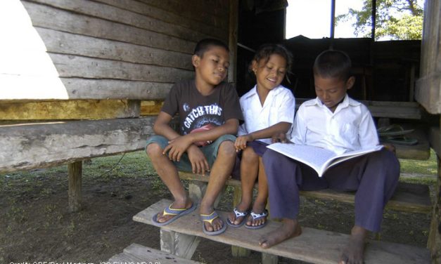 Two boys and a girl reading on a step, Honduras