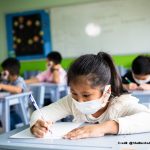 Children wearing face masks sitting at their desks in the classroom.