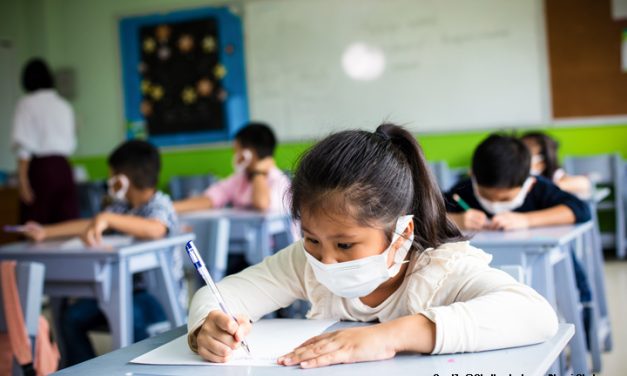 Children wearing face masks sitting at their desks in the classroom.