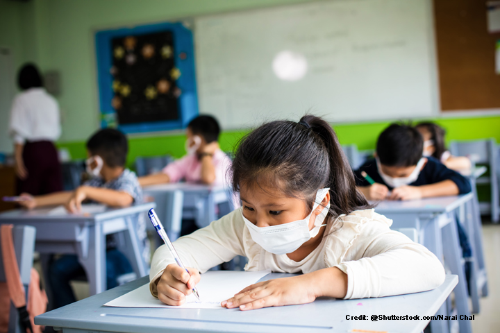 Children wearing face masks sitting at their desks in the classroom.