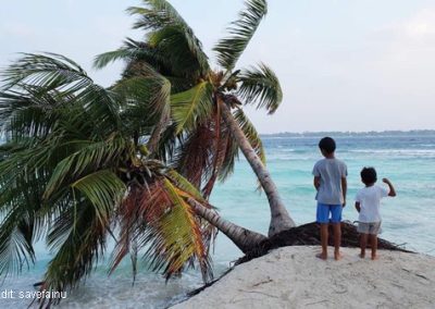 2 children on a small island where water levels are rising and palm trees are falling into the water.