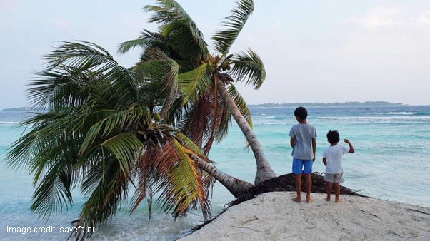 2 children on a small island where water levels are rising and palm trees are falling into the water.