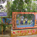 Two boys stand behind a large mock TV to pretend to be on air in a maths park in Sri Lanka.