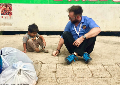 Joel David Bond plays with local refugee children, Iraq Man sitting on ground with a small child