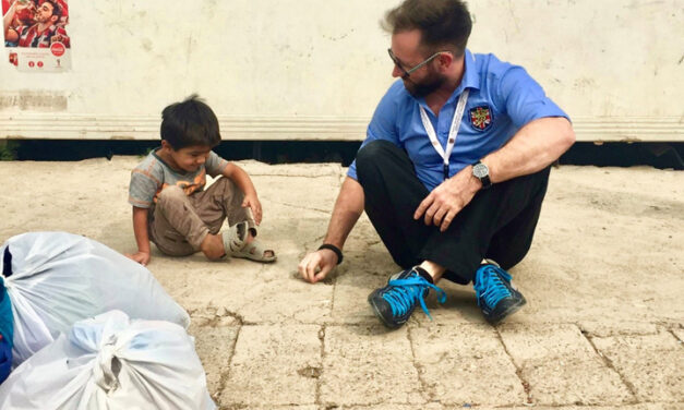 Joel David Bond plays with local refugee children, Iraq Man sitting on ground with a small child