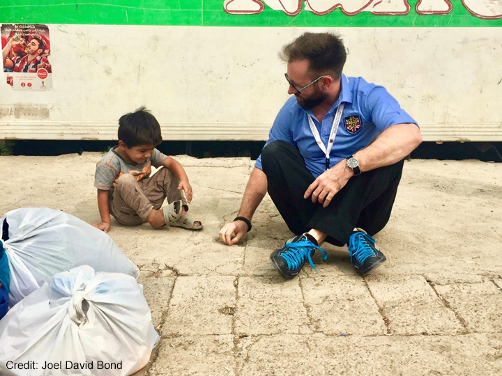 Joel David Bond plays with local refugee children, Iraq Man sitting on ground with a small child