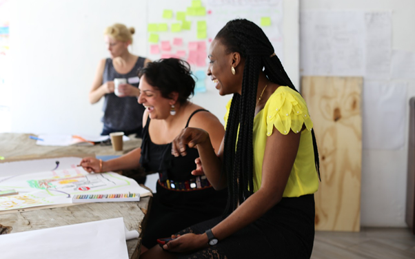 Three women working on project planning, the two in the foreground are laughing