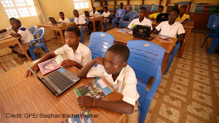 Children sit two to a desk with a laptop to share between them in computer class, Gbimsi Junior High School, Savelugu, Northern Region Ghana.