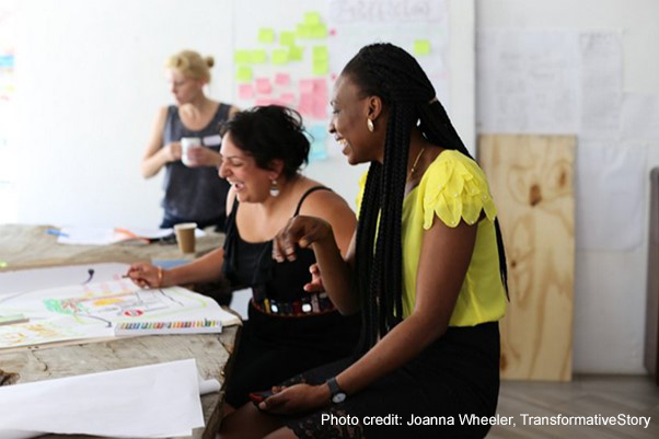 Alison Buckler in the background and Nava Derakhshani and Jennifer Agbaire laugh over some visual storytelling aides during a workshop.