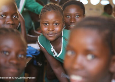 Young girls in school uniform in a rural classroom looking at the camera, Sierra Leone.