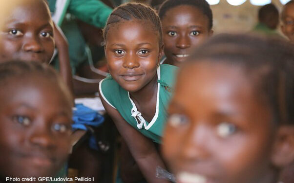 Young girls in school uniform in a rural classroom looking at the camera, Sierra Leone.