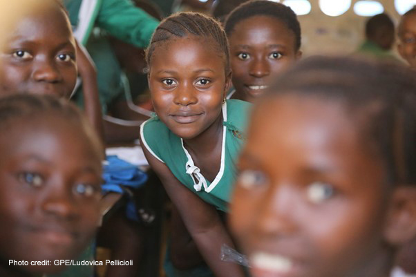 Young girls in school uniform in a rural classroom looking at the camera, Sierra Leone.