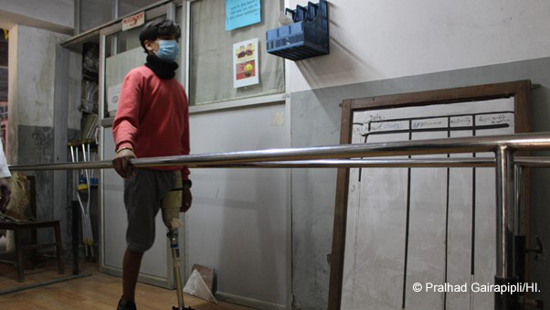 Sandip learns how to walk using his prosthetic leg at the rehabilitation centre in Kathmandu, Boy walking holding a rail 