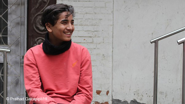 Boy smiling, wearing an orange shirt