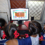 Several school girls sit around a computer for math instruction in a primary school in Chennai, India.