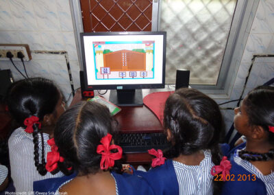 Several school girls sit around a computer for math instruction in a primary school in Chennai, India.