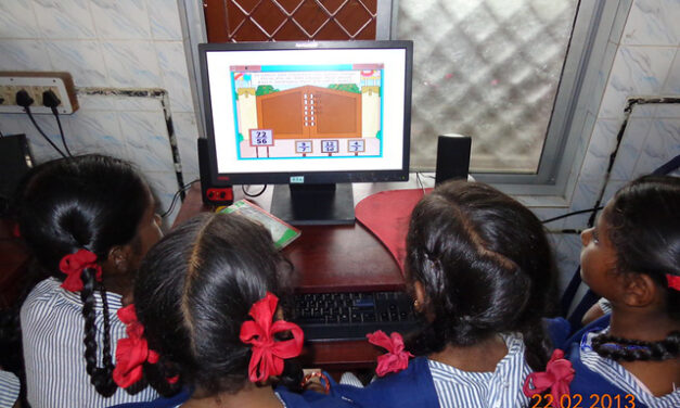 Several school girls sit around a computer for math instruction in a primary school in Chennai, India.