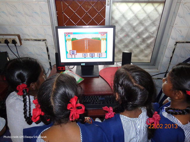 Several school girls sit around a computer for math instruction in a primary school in Chennai, India.