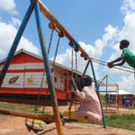Children playing on the swings in the playgrounds of their pre-school, Uganda.
