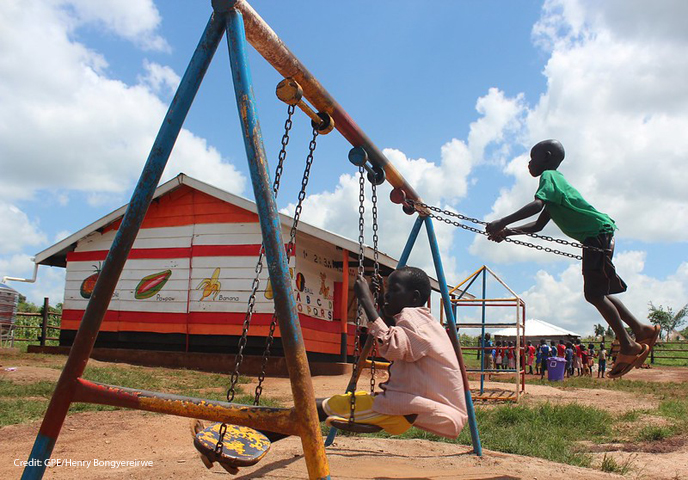 Children playing on the swings in the playgrounds of their pre-school, Uganda.