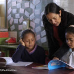 : A female teacher helps her two students in the classroom, Honduras.