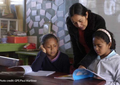 : A female teacher helps her two students in the classroom, Honduras.