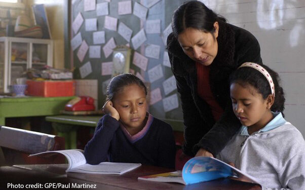 : A female teacher helps her two students in the classroom, Honduras.