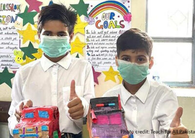 Teach For Pakistan student Abdullah (left) and a classmate with two of their recycled cars.
