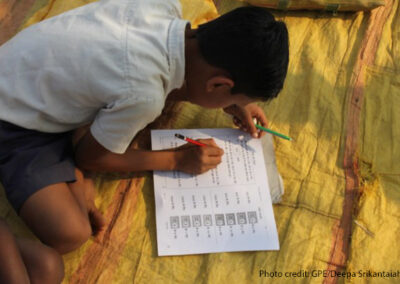 Boy sits on a rug studying with his workbook, India.