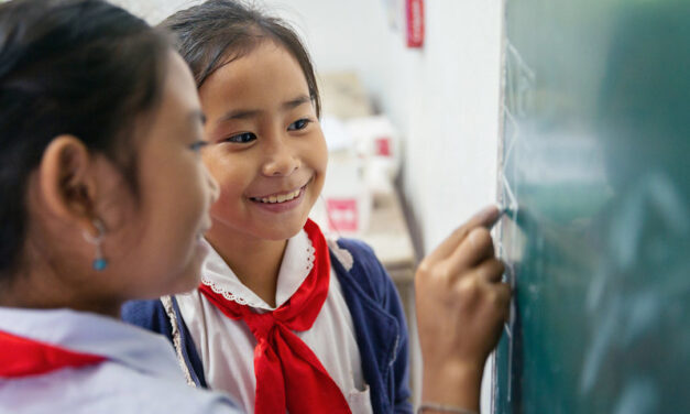 Two fourth grade girl students look at the blackboard together, Somsanouk Primary School, Pak Ou District, Lao PDR.