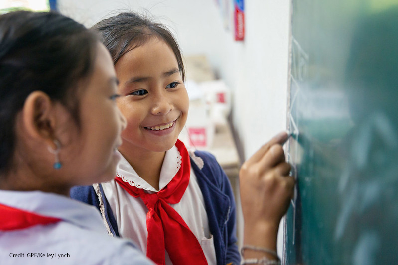 Two fourth grade girl students look at the blackboard together, Somsanouk Primary School, Pak Ou District, Lao PDR.