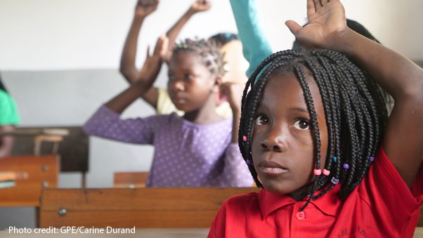 Girl puts up her hand in a newly-built classroom in Mozambique after schools were partially or full destroyed by Cyclone Idai in 2019.