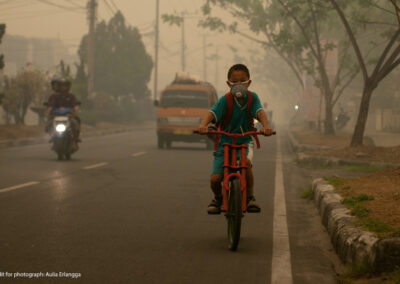 Boy in Thailand riding a moped in the smog with a face mask
