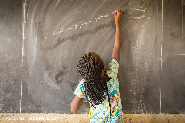 Student reaches up to write in French on the blackboard in Class 3 at the Sandogo ‘B’ Primary School, District 7, Ouagadougou, Burkina Faso.